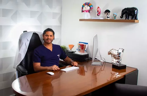 Dr Rene Zamora sentado en su consultorio urologico en Queretaro, junto a simbolos decorativos y elementos institucionales.